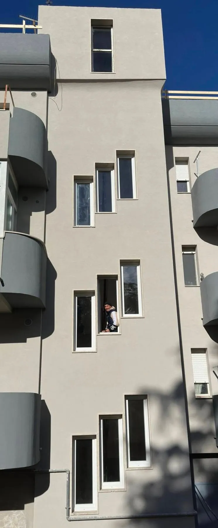 Facciata di un palazzo con le finestre del vano scala sfalsate, tutte in PVC bianco